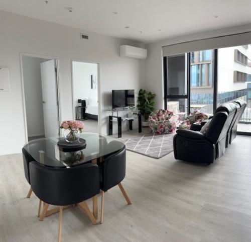 ein Wohnzimmer mit einem Glastisch und schwarzen Stühlen in der Unterkunft 2 Bedrooms apprtmt Plus Underground Parking in CBD in Christchurch