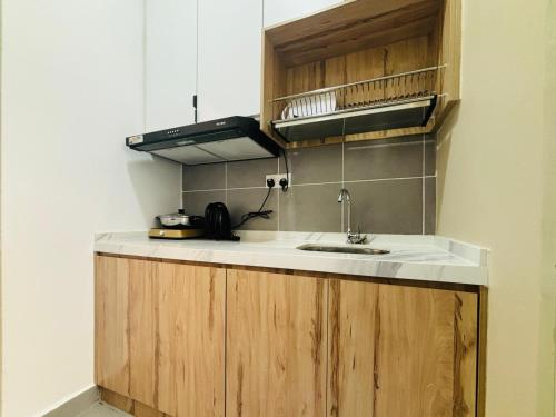 a kitchen with a sink and wooden cabinets at Youth City Residence Nilai in Nilai
