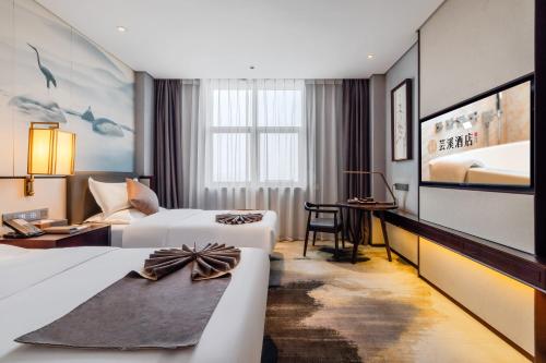 a hotel room with two beds and a desk at 丽呈東谷酒店保定客运中心店 in Baoding