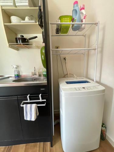 a small kitchen with a sink and a washing machine at グレース大磯 in Oiso