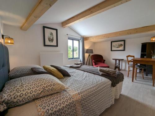 a bedroom with a large bed and a table at Gîte avec piscine chauffée, jardin clos et WiFi à Baignes - FR-1-653-264 in Baignes-Sainte-Radegonde