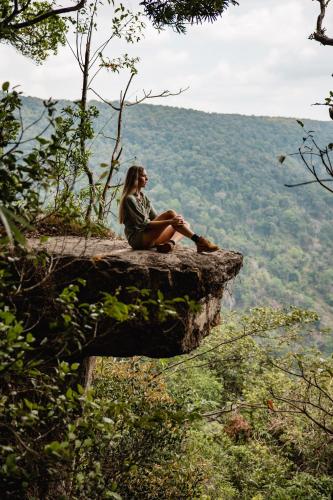 a woman sitting on the edge of a cliff at Te Mata Glamping in Nong Nam Daeng