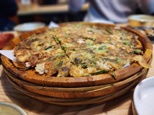 a pizza in a wooden bowl on a table at Let's Stay in Seoul