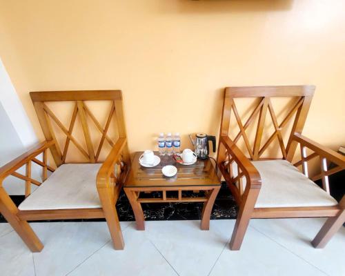 two chairs and a wooden table with a tea set on it at New Sun Hotel Sapa in Sa Pa