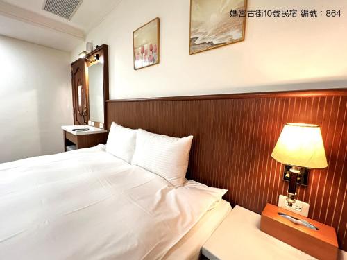 a bedroom with a white bed and a lamp at 媽宮古街10號 in Magong