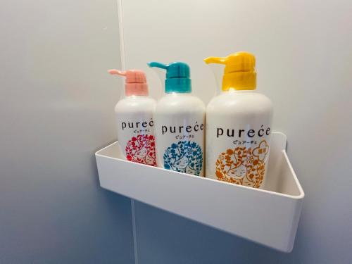 a shelf with three bottles of juice in a bathroom at 宿の夜夜 広々一棟貸し駐車場2台 浴室2箇所 大家族グループ旅行に最適 静かな環境 in Omihachiman