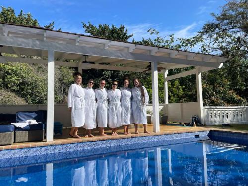 a group of people in white robes standing next to a swimming pool at Villa Celeste Bed & Breakfast in El Río Arriba