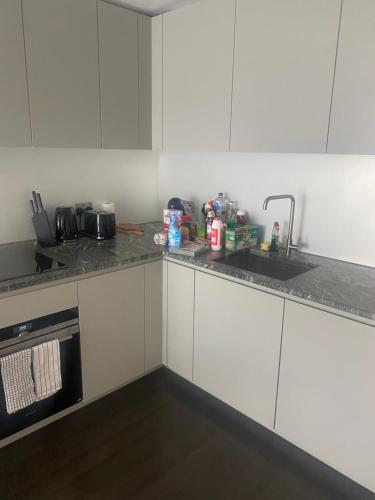 a kitchen with white cabinets and a sink at Luxury stay near O2 and canary wharf in London