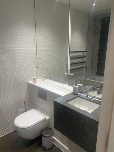 a bathroom with a toilet and a sink and a mirror at Luxury stay near O2 and canary wharf in London