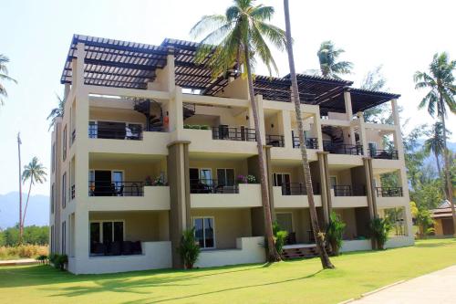 un bâtiment avec des palmiers devant dans l'établissement Blue Haven Bay Villa 21D and Resort Apartments, à Ko Chang