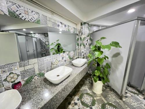 a bathroom with two sinks and a mirror and a potted plant at Khu Du Lịch Tea Bobla Waterfall in Di Linh
