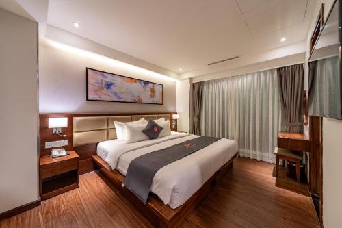 a hotel room with a large bed and a television at Edoya Hotel Ben Thanh in Ho Chi Minh City