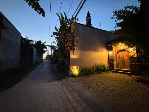 an empty alley with a building and a wooden door at Alam Petanu in Ubud