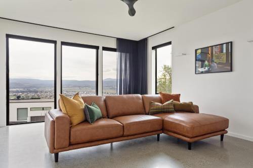 a brown leather couch in a room with windows at Lachlan Retreat,Trevallyn in Launceston