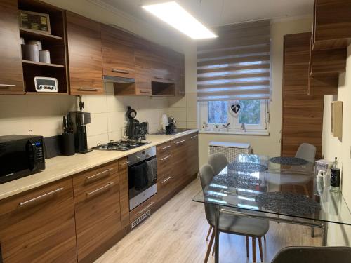 a kitchen with wooden cabinets and a glass table at Relax apartman in Siófok