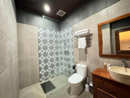 a bathroom with a toilet and a sink and a mirror at Alam Petanu in Ubud