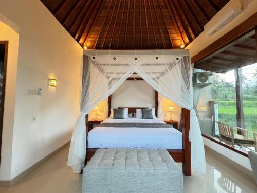 a bedroom with a large bed with a canopy at Alam Petanu in Ubud