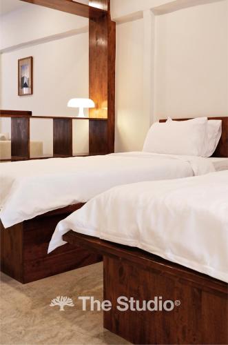 two beds with white sheets in a bedroom at The Studio in Loei