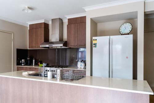a kitchen with a refrigerator and a clock on the wall at Point Cook Spacious Maison in Point Cook
