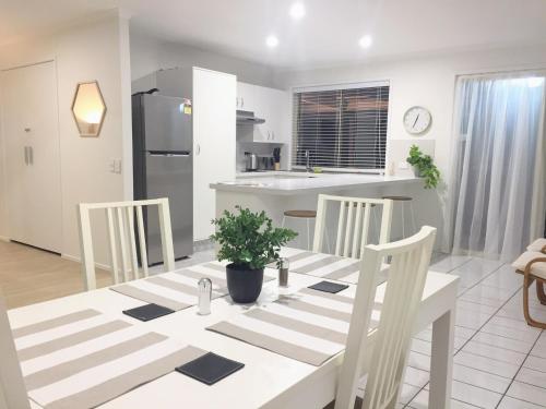a kitchen and dining room with a white table and chairs at Robin Joy in Gold Coast