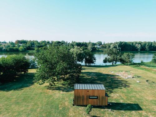 une petite partie assise au sommet d'un champ à côté d'un lac dans l'établissement Loire River Tranquility by Tiny Away, à Saint-Pryvé-Saint-Mesmin