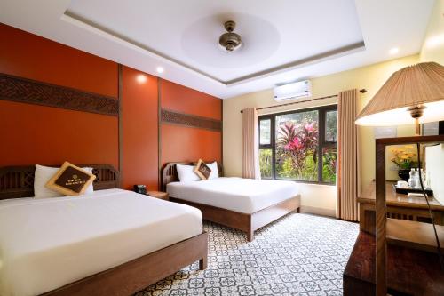 a hotel room with two beds and a window at LumiGarden Tam Coc Resort in Ninh Binh