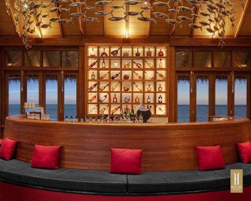 a bar in a restaurant with red pillows at Heritance Aarah - Premium All Inclusive - 40 Minutes away from Male by Seaplane in Raa Atoll