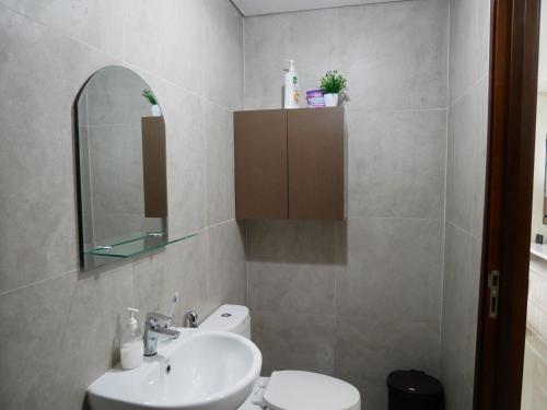 a bathroom with a sink and a toilet and a mirror at Meisterstadt Pollux Habibie in Batam Center