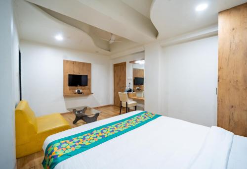 a bedroom with a white bed and a yellow chair at Treebo Kamal Regency in Bhopal