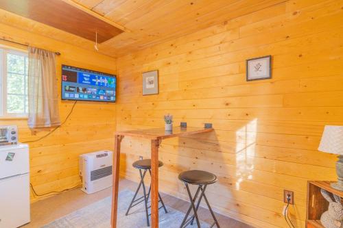 a kitchen with a wooden wall with a table and stools at The Skarland Trail Cabin in Fairbanks