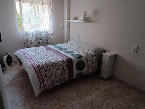 a bedroom with a bed with a flowered blanket and a window at Galatea Arena in Arenales del Sol