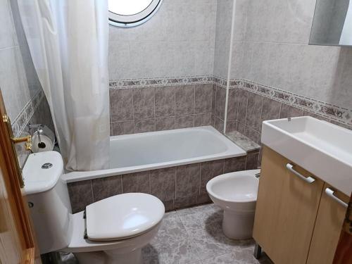 a bathroom with a toilet and a tub and a sink at Galatea Arena in Arenales del Sol