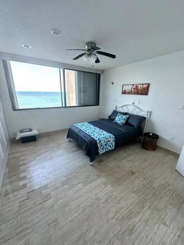 カンクンにあるBeautiful Beachfront Apartment with Pool Relaxing Getawayのベッドと天井扇風機のある寝室