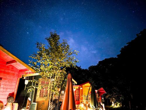 a building with an umbrella and a tree at night at 星逢える宿ー森のコテージ気仙沼 in Kesennuma