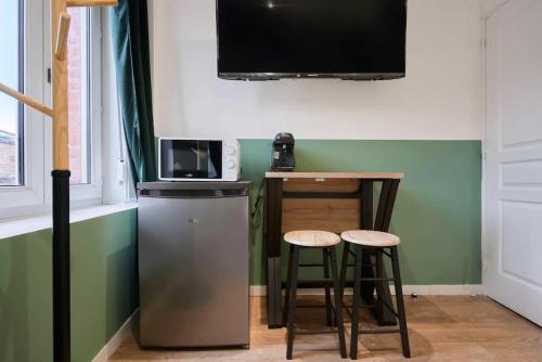 - une petite cuisine avec un four micro-ondes et deux tabourets dans l'établissement Green Leaf - Olympe Suites & Spa - Tourcoing, Lille, à Tourcoing