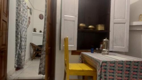 a dining room with a table and a yellow chair and a table andearcher at Fruit Bowl in Rāmgarh