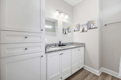 a white bathroom with two sinks and a mirror at DERBY BLUE A- Ocean Views- Garage & EV Charger in Myrtle Beach