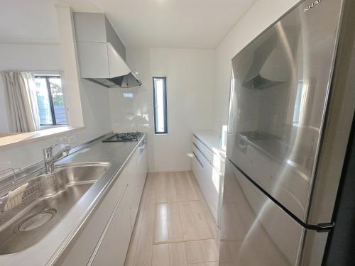 a white kitchen with a stainless steel refrigerator at YUIhouse in Nago