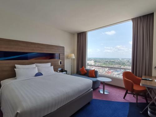 a hotel room with a bed and a large window at Novotel Taiping in Taiping