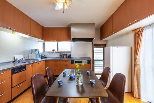 a kitchen with a table and chairs and a refrigerator at Rakushinkan Villa in Yufuin