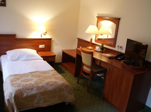 Habitación de hotel con cama y escritorio con TV. en Gościniec Sucholeski, en Suchy Las