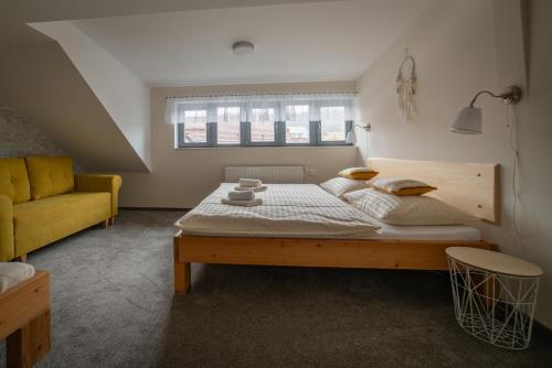 a bedroom with a bed and a yellow couch at Stará Celnice Kvilda in Kvilda