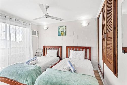two beds in a room with white walls at Capricorn Whitsunday in Cannonvale