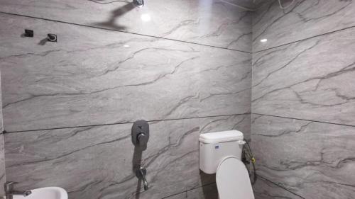 a bathroom with a toilet and a stone wall at Nain Guest House in Ujjain