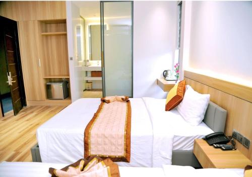 a hotel room with two beds and a mirror at Khách Sạn LUCIEN HOTEL Quy Nhơn in Quy Nhon