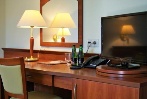 a desk in a hotel room with a television and drinks on it at Gościniec Sucholeski in Suchy Las