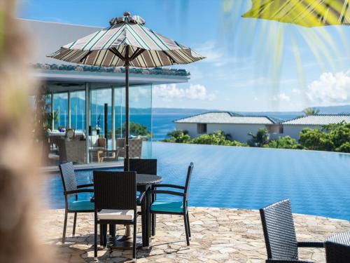 a table with chairs and an umbrella next to a pool at Oriental Hills Okinawa in Onna