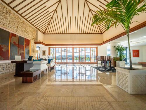 a large lobby with a palm tree in the center at Oriental Hills Okinawa in Onna