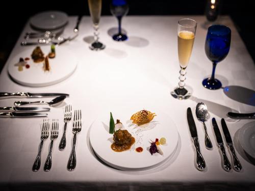a table with two plates of food and glasses of wine at Oriental Hills Okinawa in Onna