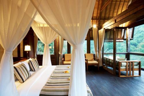 a bedroom with a bed with drapes at Bagus Jati Health & Wellbeing Retreat in Tegalalang